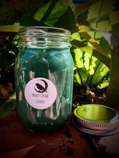 a green jar with a label on it sitting next to a potted plant in the background