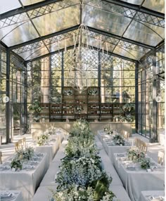 a dining room with tables and chairs covered in white linens, surrounded by glass walls