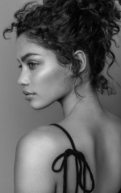 a black and white photo of a woman with curly hair wearing a halter top