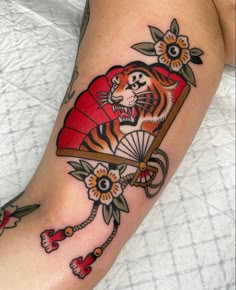 a tiger tattoo on the leg of a woman with an umbrella and flowers around it