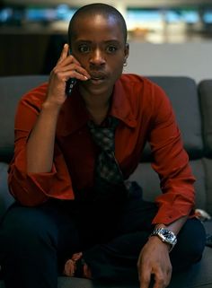 a person sitting on a couch talking on a cell phone while wearing a red shirt and tie