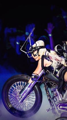 a woman on a motorcycle in the middle of a stage with other people behind her