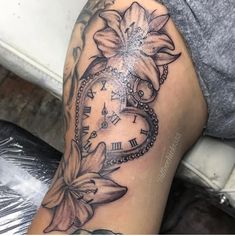 a woman's leg with a clock and flower tattoo on it