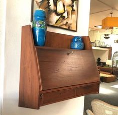 a wooden shelf with two blue vases on it and a painting above the shelf