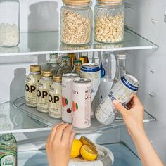 a person reaching into an open refrigerator to pick up some food from the bottom shelf