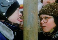 two young children wearing winter hats and scarves, one is biting the other's ear