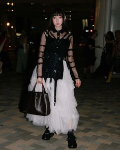 a woman in black and white dress holding a brown purse