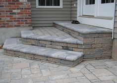 the steps are made of stone and have been placed in front of a brick house