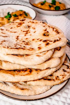 a stack of pita bread sitting on top of a plate next to bowls of food