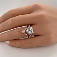 a woman's hand with a diamond ring on her finger and the other hand holding an engagement ring