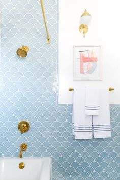 a bathroom with blue and white wallpaper, gold fixtures and towels on the rack