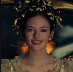 a woman in a dress with a gold crown on her head smiling at the camera