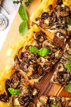 a pizza with mushrooms, cheese and basil on a cutting board