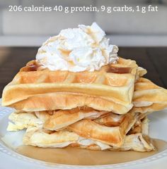 a stack of waffles topped with whipped cream and syrup on a white plate