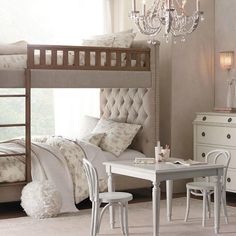 a bedroom with a bunk bed, desk and chair in it next to a chandelier