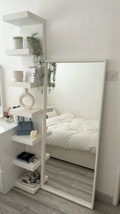 a bedroom with a large mirror on the wall next to a white bed and nightstand