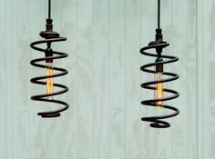 two light bulbs hanging from the side of a wooden wall with spiral springs attached to them