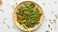 a wooden bowl filled with broccoli and other food on top of a table