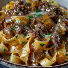 a close up of a bowl of food with noodles and meat in sauce on it