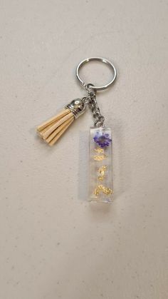 a keychain with a flower in it and two tassels attached to it