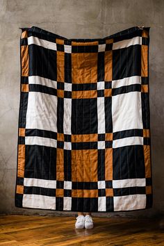 a black and orange checkered blanket with white shoes on the floor next to it