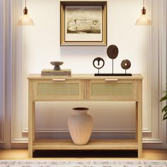 a white vase sitting on top of a wooden table next to a wall mounted painting