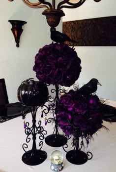 purple flowers and black candlesticks on a white tablecloth with a chandelier in the background