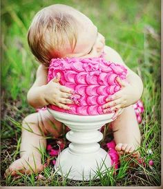 a baby sitting in the grass with a pink blanket on it's back