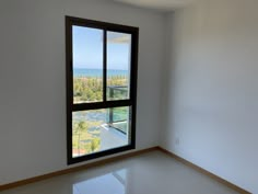 an empty room with a large window overlooking the water and trees in front of it