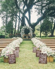 an image of a wedding ceremony with flowers on the aisle and wooden benches lined up