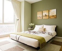 a green bedroom with white bedding and two paintings on the wall above the bed