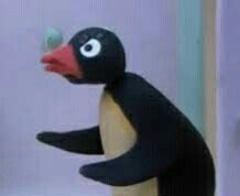 a toy penguin is standing on its hind legs and holding something in it's mouth