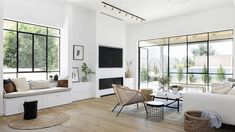 a living room filled with furniture and windows next to a wooden floor covered in plants