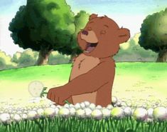 a cartoon bear sitting in the grass with its mouth open