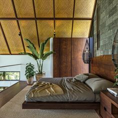 a bed sitting under a wooden ceiling next to a plant on top of a table