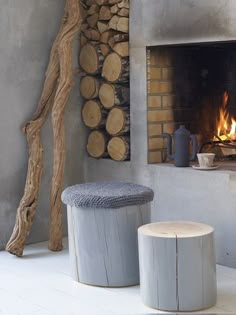 two stools sitting next to each other in front of a fire place with logs