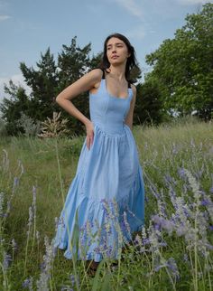 A truly special dress. With rich black ribbon tie straps, a corset bodice, and sweeping ruffle hem the Mirabelle Dress is dramatic, romantic beauty at its best and one of our most popular styles. Made in a lightweight blue gingham linen with a sateen finish that gives the linen a subtle dressy luster. A showstopper of a dress made for special moments, celebrations, or romantic getaways.