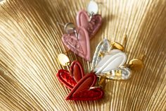 three heart shaped brooches sitting on top of a gold plate