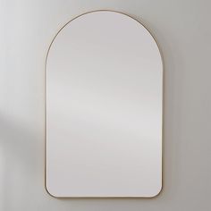 a white wall with a gold framed mirror