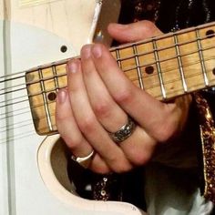 a close up of a person playing an electric guitar with their hands on the strings