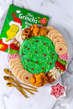 the grinch's green cake is surrounded by cookies, pretzels and candy