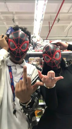 two people wearing spider man masks and pointing fingers at the camera in a grocery store