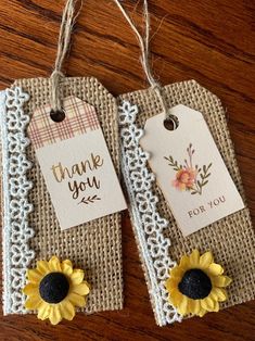 two tags with sunflowers on them are hanging from twine lace doily