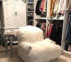 a white chair sitting in front of a closet filled with clothes