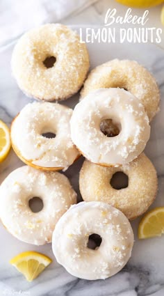 glazed lemon donuts on a white marble surface with sliced lemons and the words baked lemon donuts above them