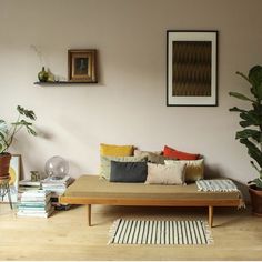 a living room filled with lots of furniture next to potted plants and pictures on the wall