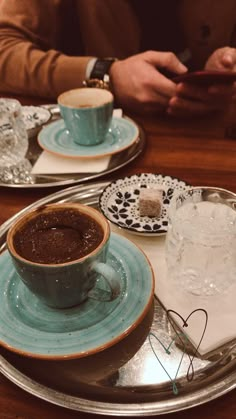 two plates with cups and saucers on them sitting on a table next to each other