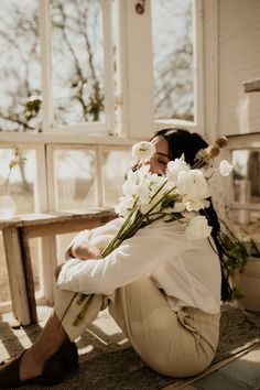 a woman sitting on the ground with flowers in her hair