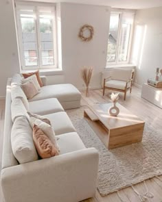 a living room filled with white furniture and lots of pillows on top of it's couches