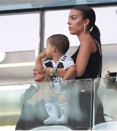 a woman holding a small child in her lap while sitting next to another person on a bench